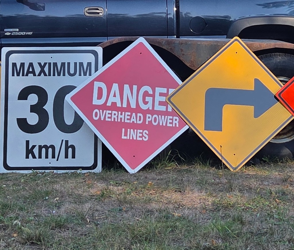 Custom reflective traffic and safety signs including speed limit, danger overhead power lines, and directional warning signs