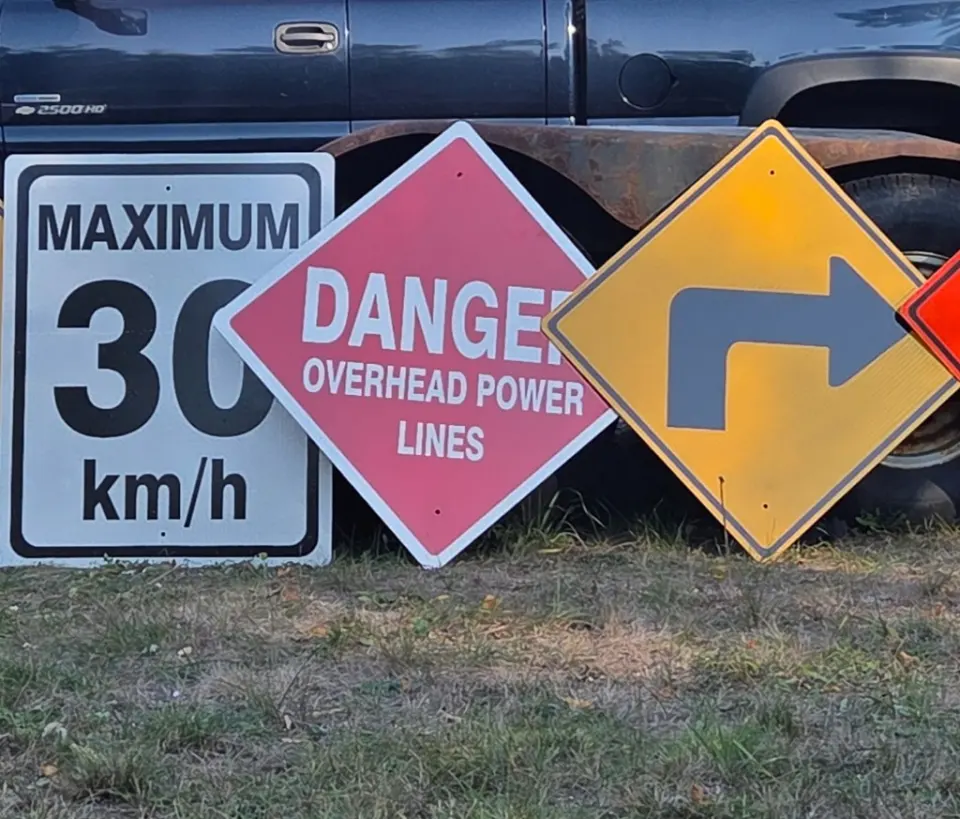 Custom reflective traffic and safety signs including speed limit, danger overhead power lines, and directional warning signs